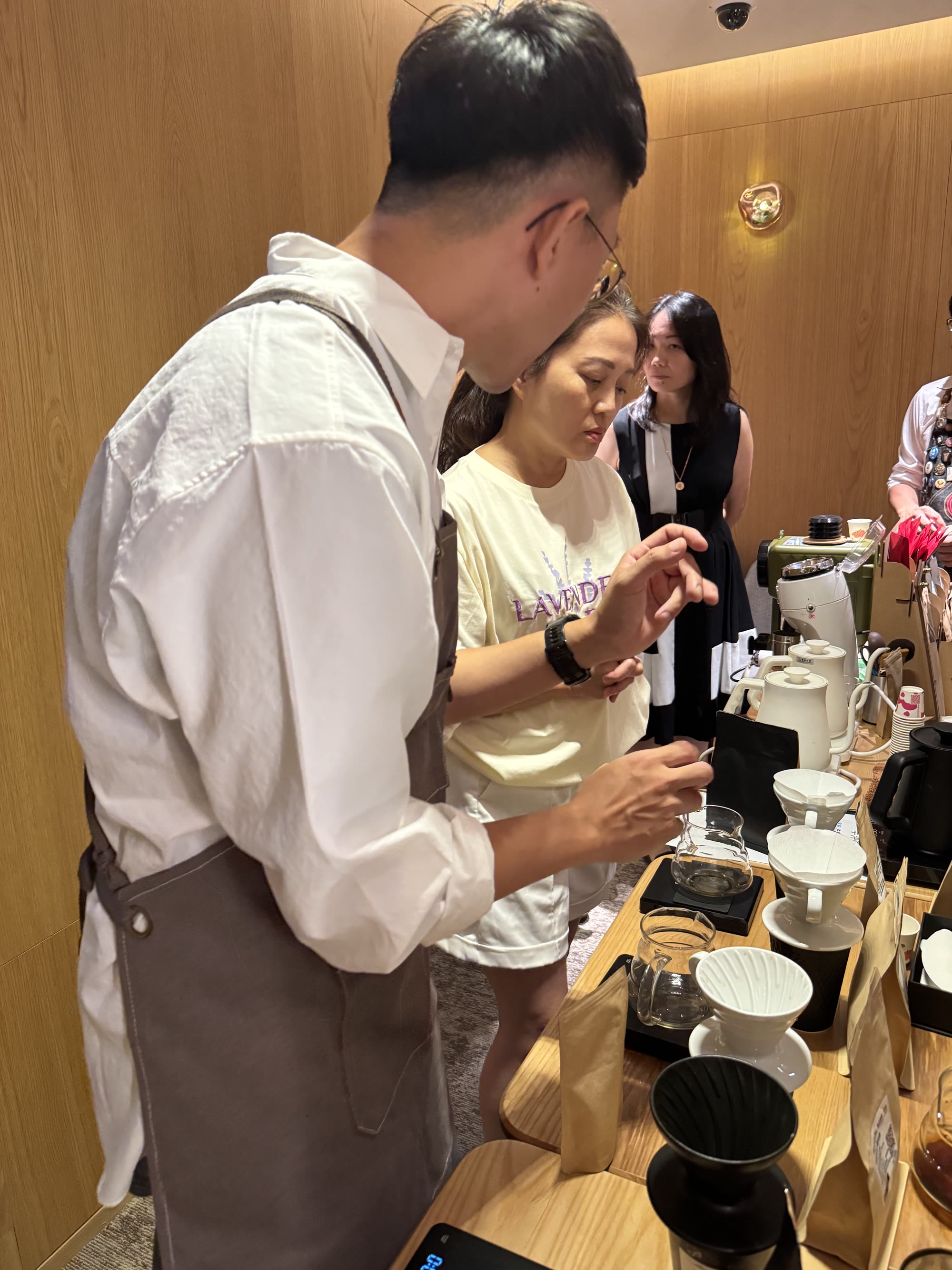 阿勳站在學員旁邊，教她看濾杯